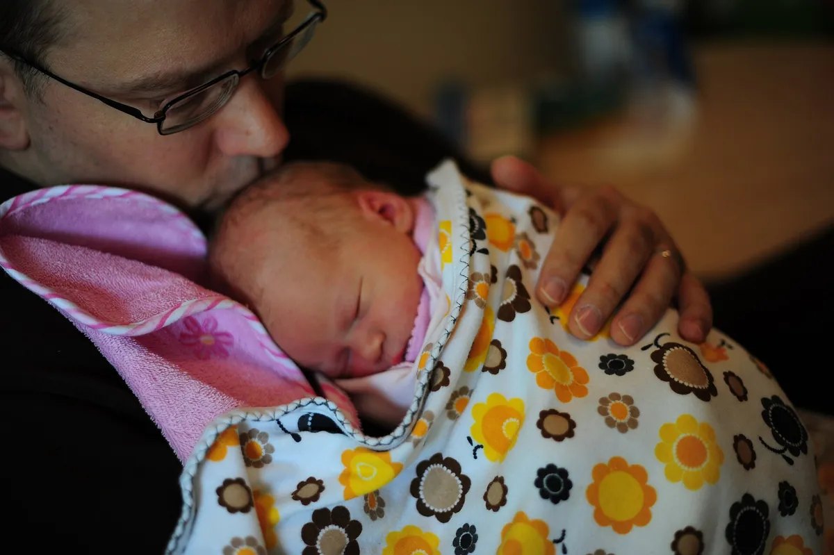 New dad holding his sleeping newborn daughter against his chest